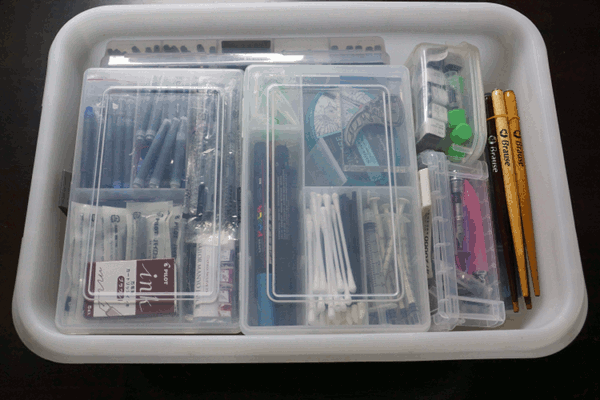 Contents of stackable storage box full of pen spare parts, dip pens, etc.